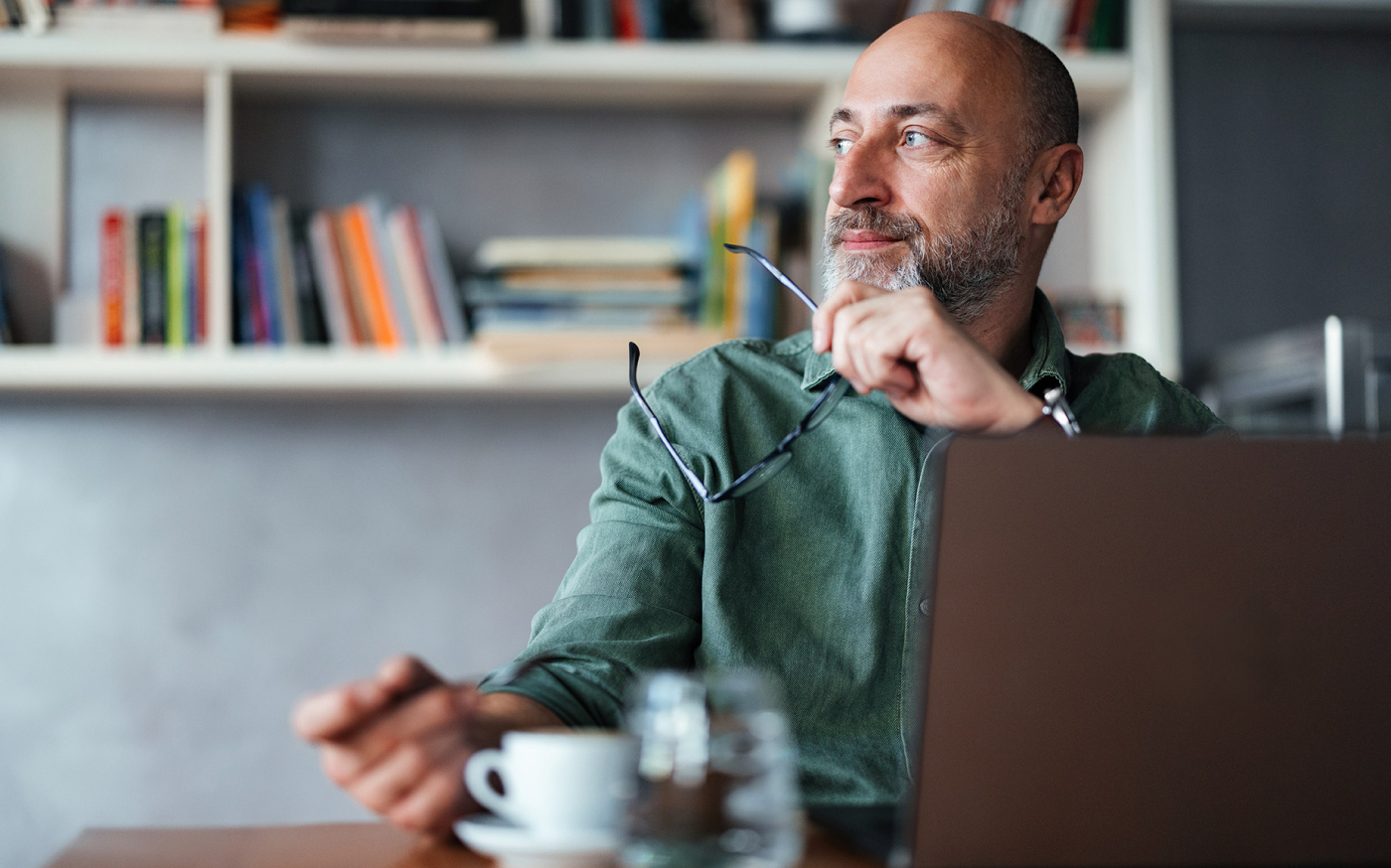 Person sitting at a table looking off to the side and thinking