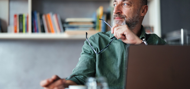 Person sitting at a table looking off to the side and thinking